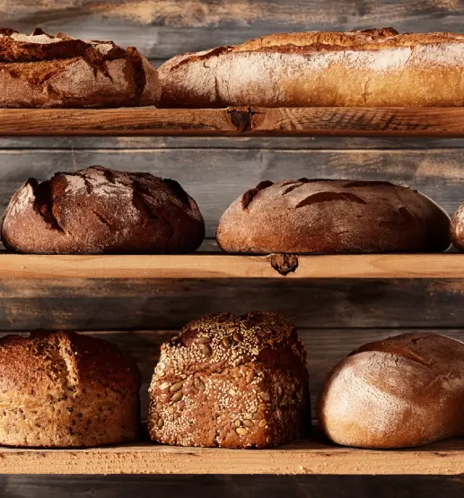 Group 4 (9) A wooden shelf with several different types of bread.