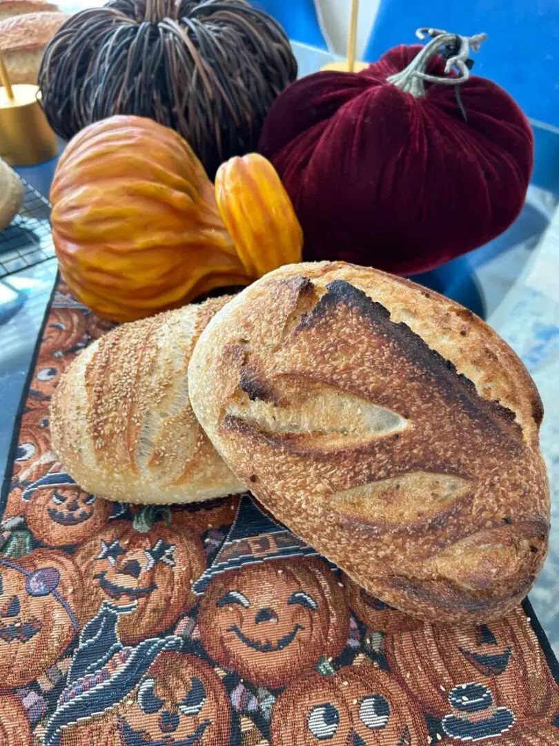 Two loaves of bread on a table with pumpkins.