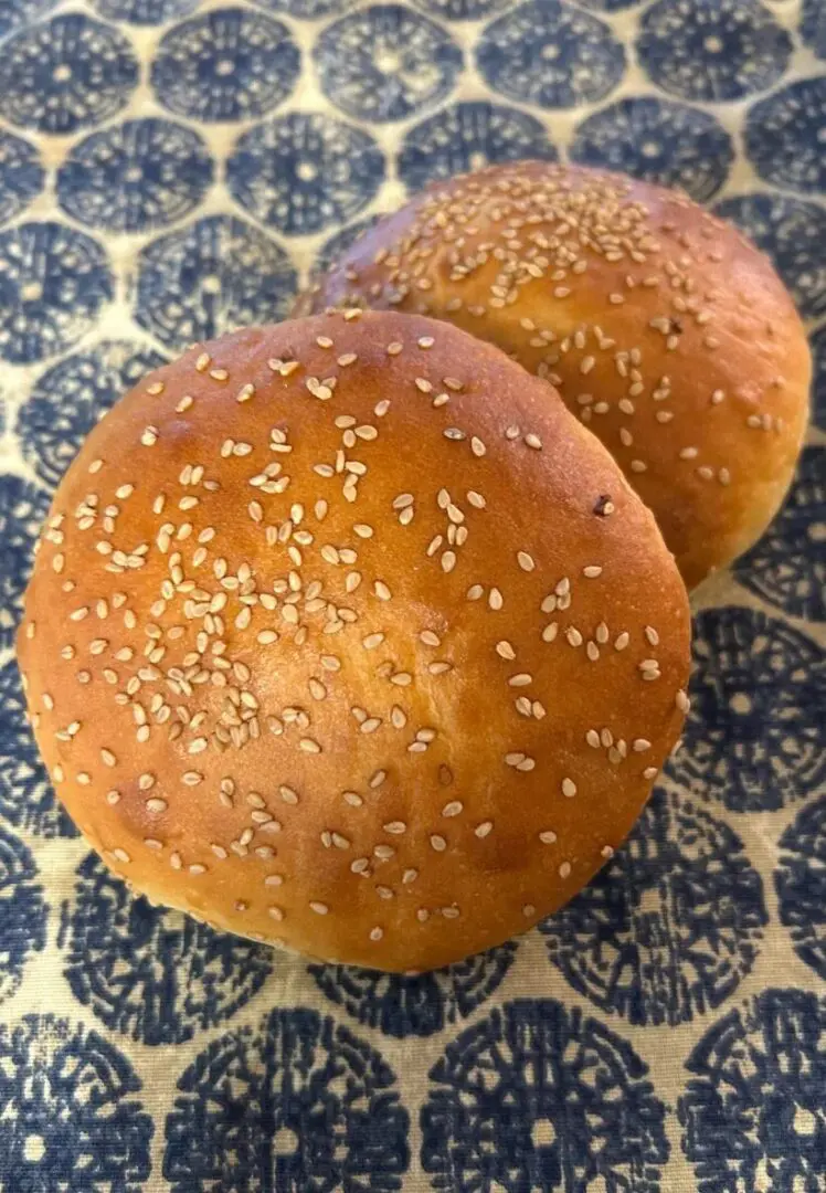 Two buns with sesame seeds on a blue and white plate.