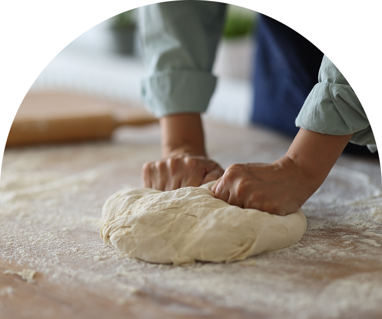 A person kneads dough on the floor.