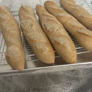 Whole grain baguettes cooling on a rack.